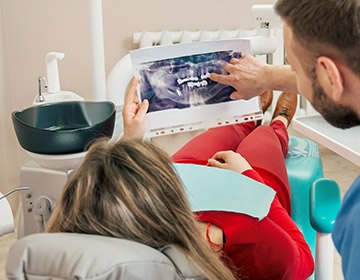 Dentist and patient looking at dental x rays on tablet screen