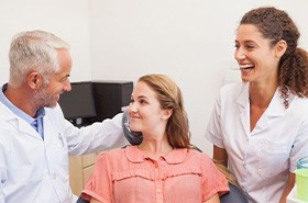 Patient in pink blouse talking to dental team