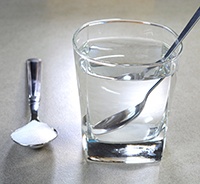 Spoonful of salt next to glass of water