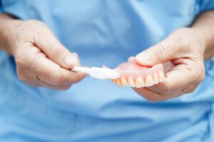 Dentist demonstrating how to brush dentures