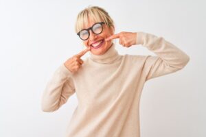 Happy older woman pointing at her teeth